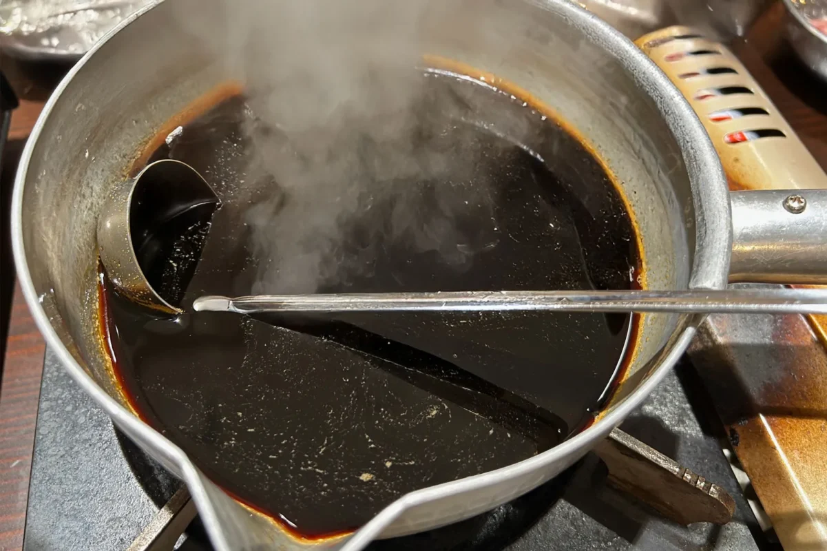 A pot with soy sauce poured into it. A photo of the pot where you can see the rising steam and aroma.